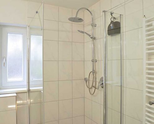 Badezimmer 1 mit Fenster, Dusche, WC, großem Spiegelschrank, Kosmetikspiegel und Föhn.